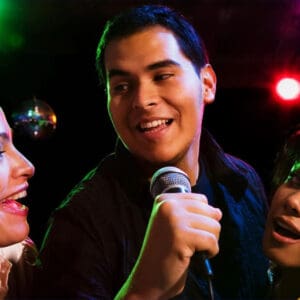 A man and two women are singing into microphones.